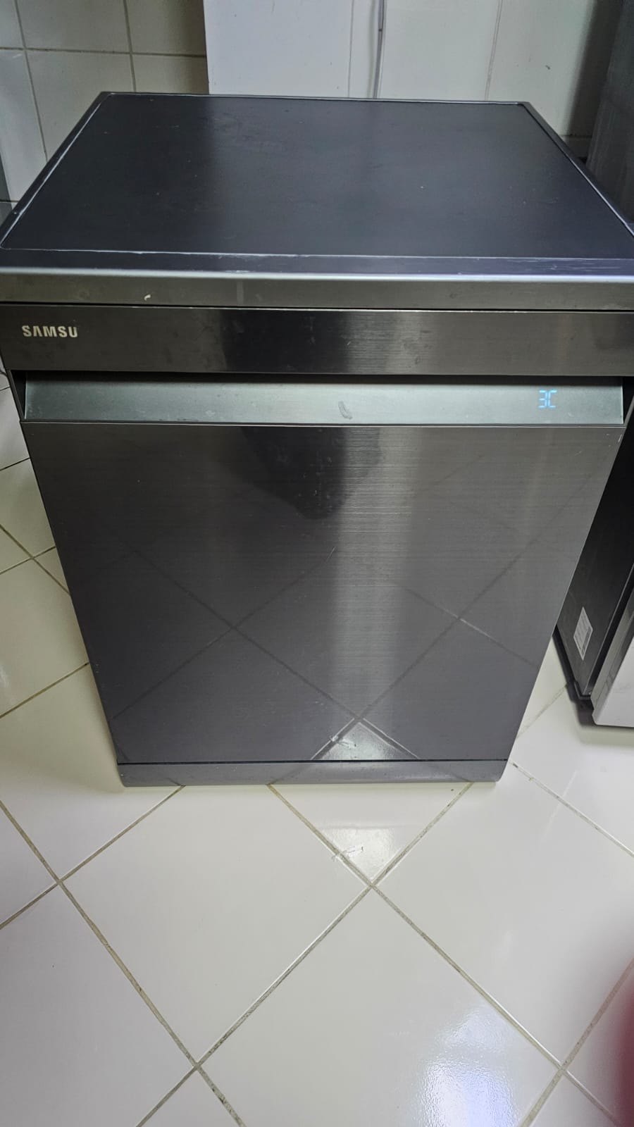 Dark steel freestanding dishwasher in a kitchen on a UAE home visit