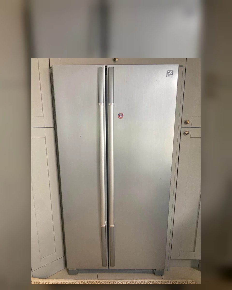 Silver side-by-side refrigerator fitted between cream kitchen cupboards
